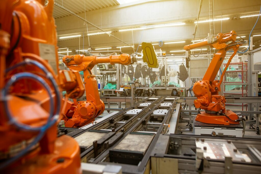 Autozulieferer: Fabrikhalle mit orangefarbenen Industrierobotern