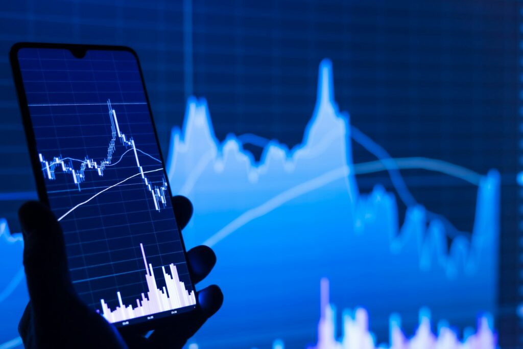 DAX Ausblick: Smartphone mit Aktienchart vor einem Börsenmonitor