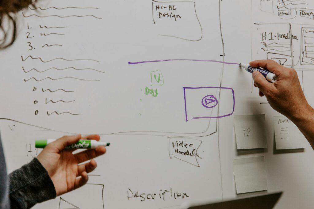 Managementmodelle entwickeln: Zwei Personen skizzieren eine Organisationsstruktur am Whiteboard