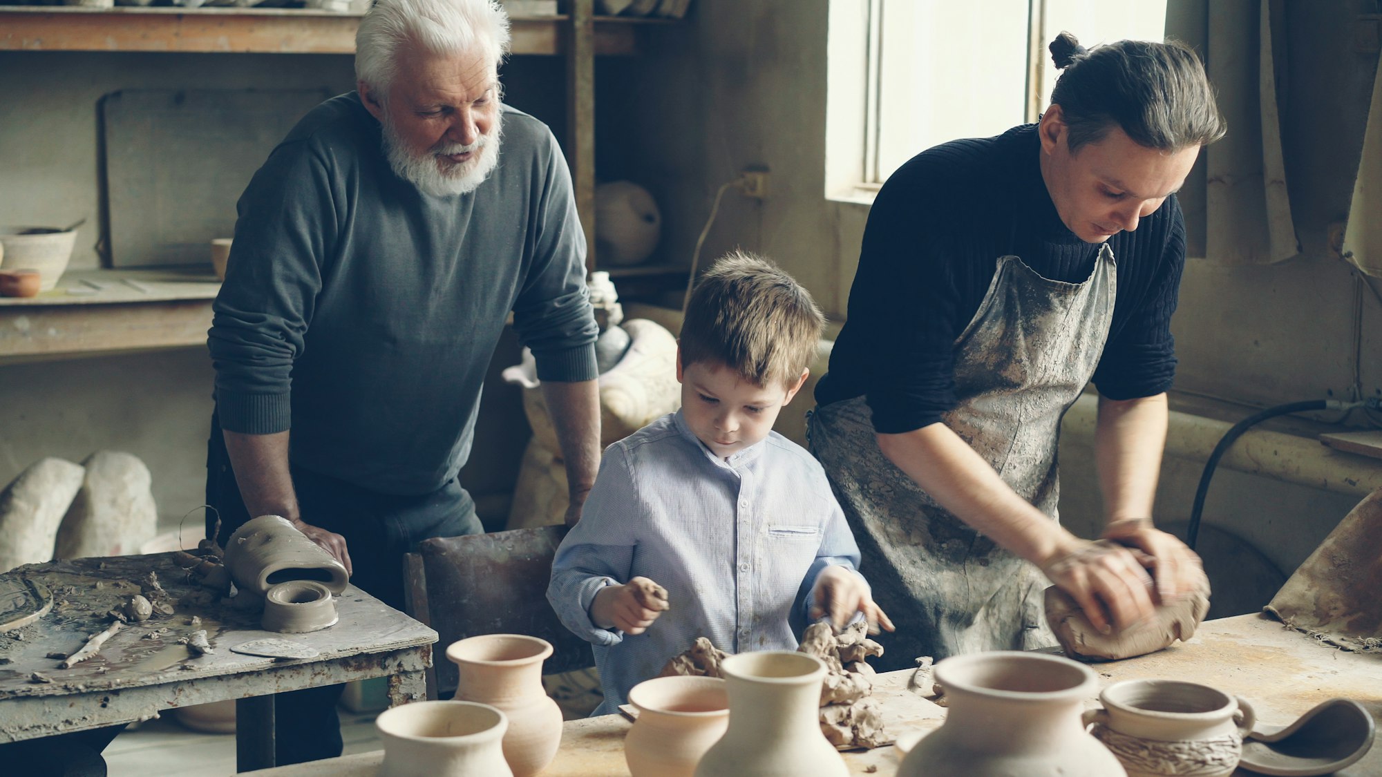 Unternehmensnachfolge im Familienunternehmen: Großvater, Vater und Sohn arbeiten gemeinsam in der Werkstatt